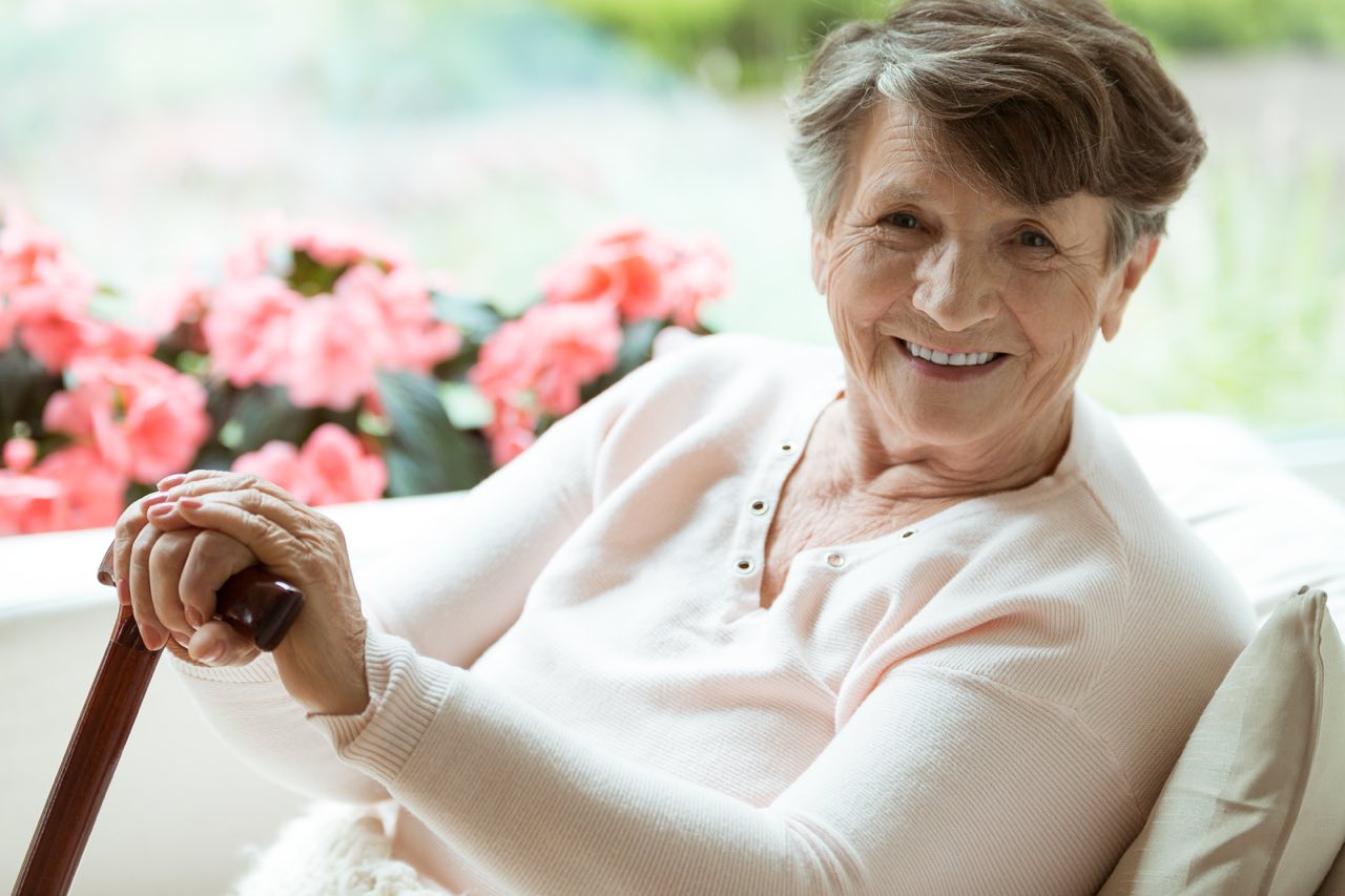 A woman happily sits with her cane. DaySpring assisted living facilities are welcoming living places in West Michigan.